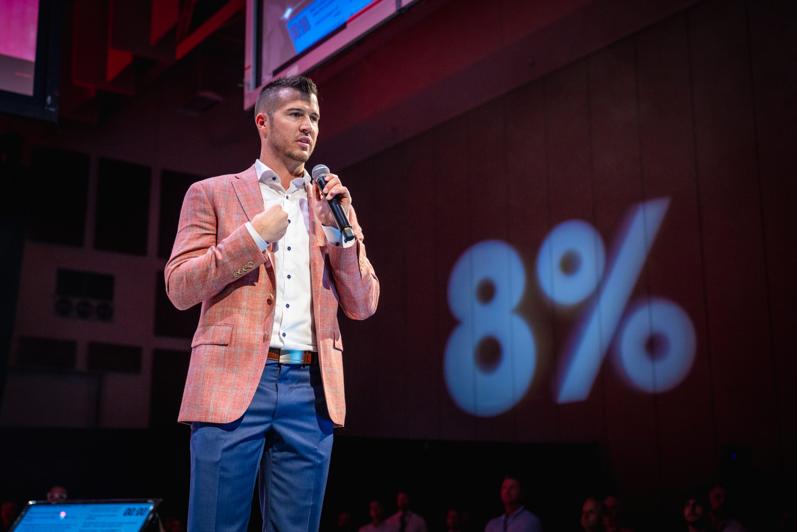 Cody on stage with 8% logo in red lighting