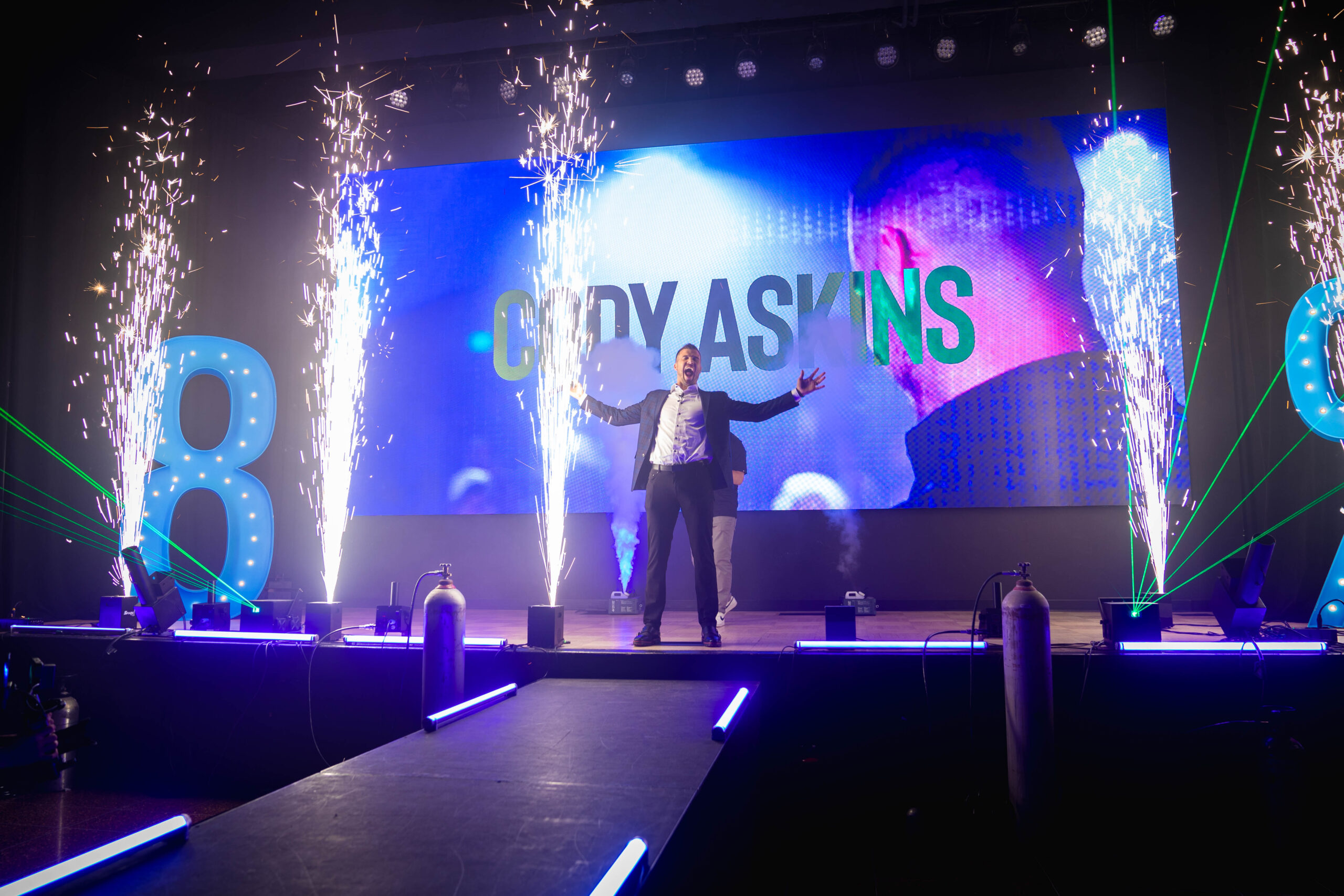 Cody Askins on stage at 8% Nation Conference with fireworks and pyrotechnics